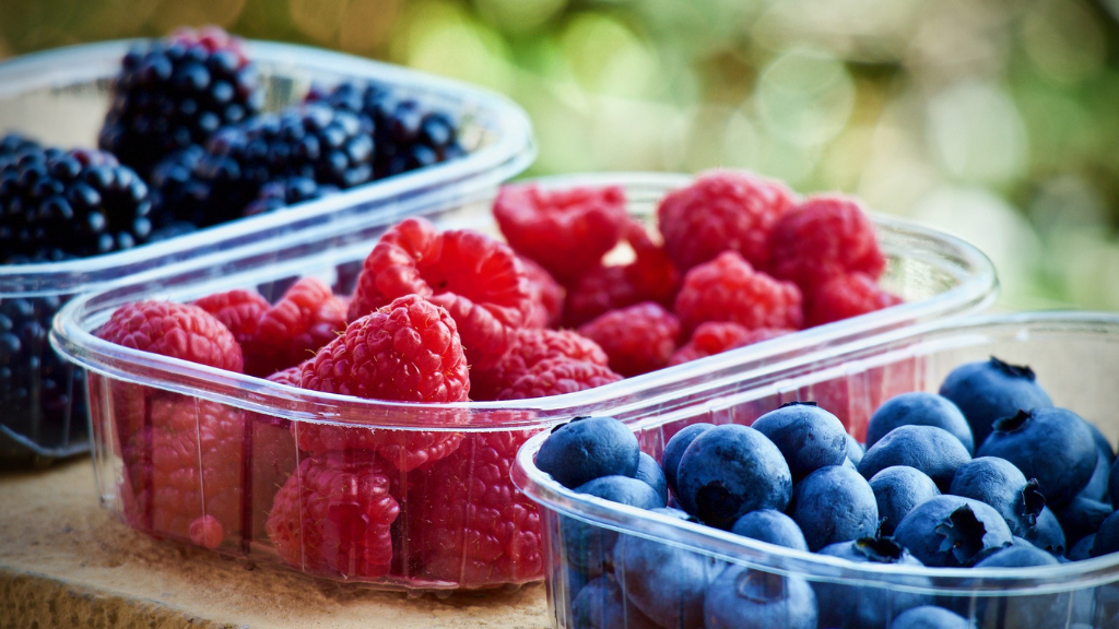 Drei Kunststoffbehälter mit frischen Heidelbeeren und Himbeeren, ansprechend verpackt